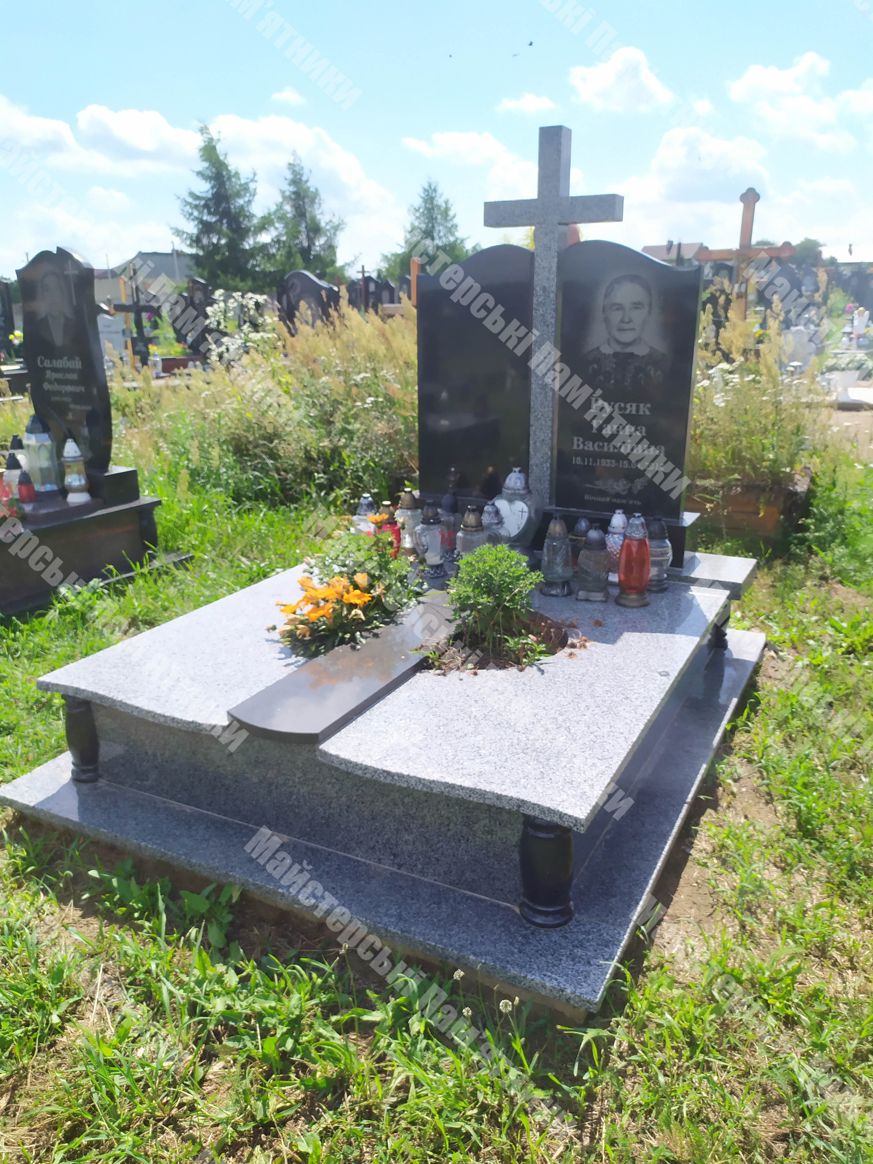 подвійний пам'ятник з покостовського граніту та гранітним хрестом між верхніми плитами