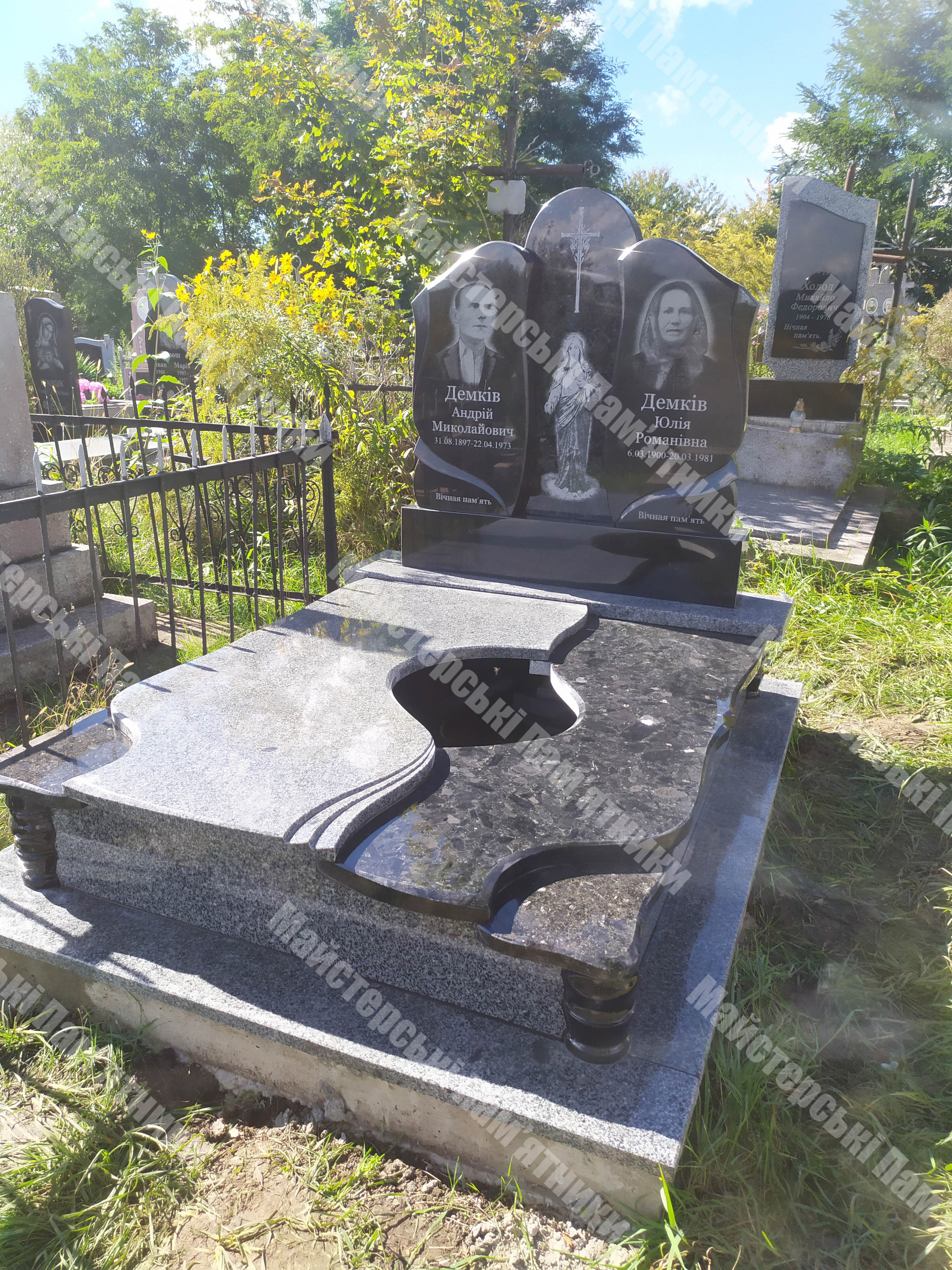 двійний пам’ятник з лабрадоритного та покостівського граніту з кругим отвором в нижній плиті